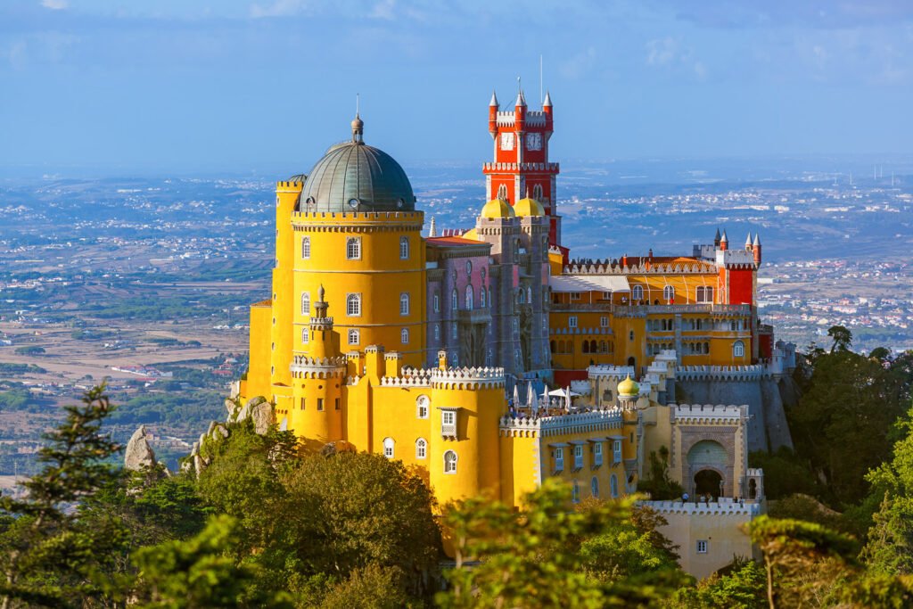 Sintra, Portugal – A colorful palace perched on a hill, surrounded by mist and autumn foliage