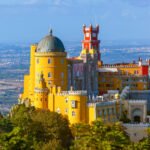 Sintra Portugal – A colorful palace perched on a hill surrounded by mist and autumn foliage
