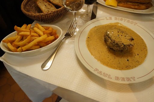 A plate of steak-frites served with golden fries at Bistro Paul Bert