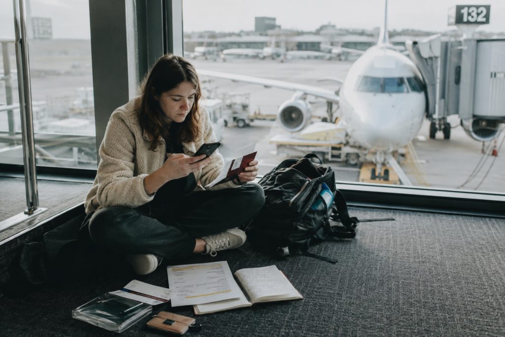 Traveller rechecking passport and itinerary details on the floor beside an airport departure gate
